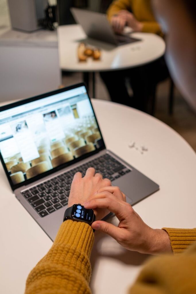 Modern office scene with adult using laptop and smartwatch, emphasizing tech integration.